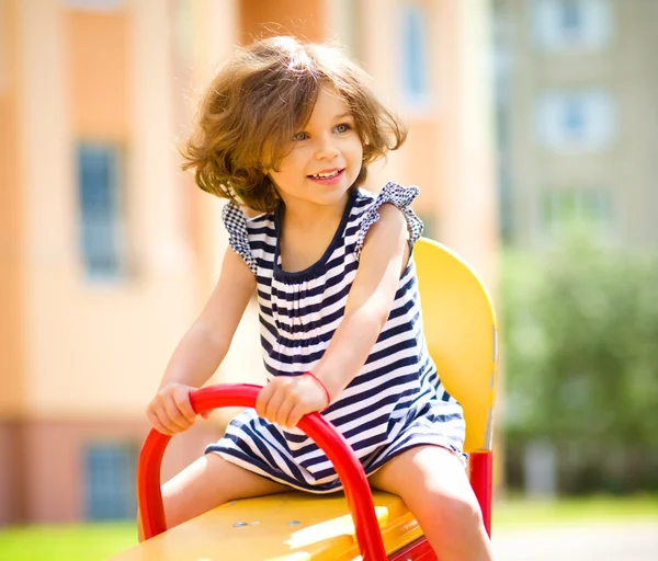 Jeune fille heureuse se balance dans l'aire de jeux — Photo