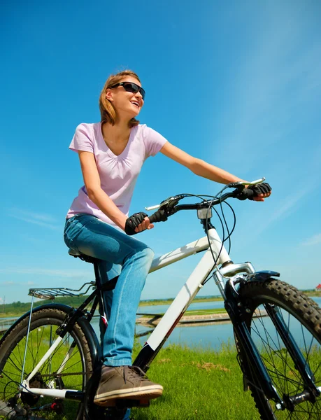 Jovem mulher está sentada em sua bicicleta — Fotografia de Stock