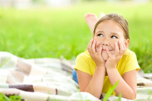 Портрет маленької дівчинки, що лежить на зеленій траві — стокове фото