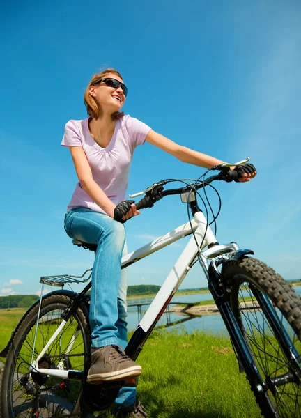 Jovem mulher está sentada em sua bicicleta — Fotografia de Stock