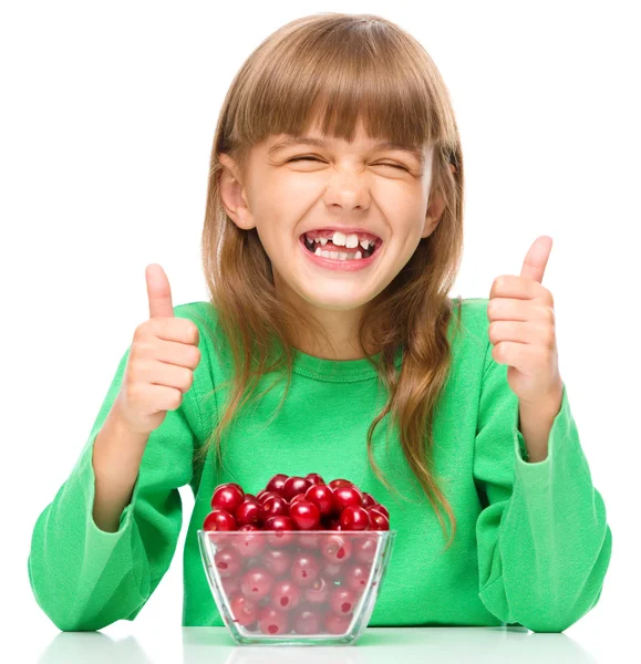 Cute girl is eating cherries showing thumb up sigh — Stock Photo, Image