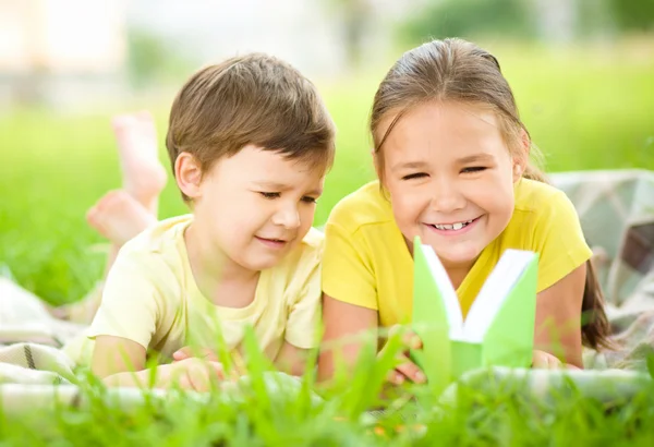 Little girl and boy are reading book outdoors — Stock Photo, Image