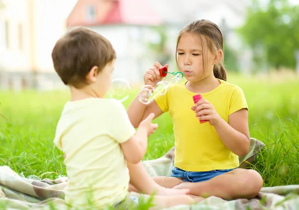 Kleine Mädchen und Jungen pusten Seifenblasen — Stockfoto