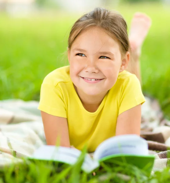 Little girl is reading a book outdoors — Stock Photo, Image