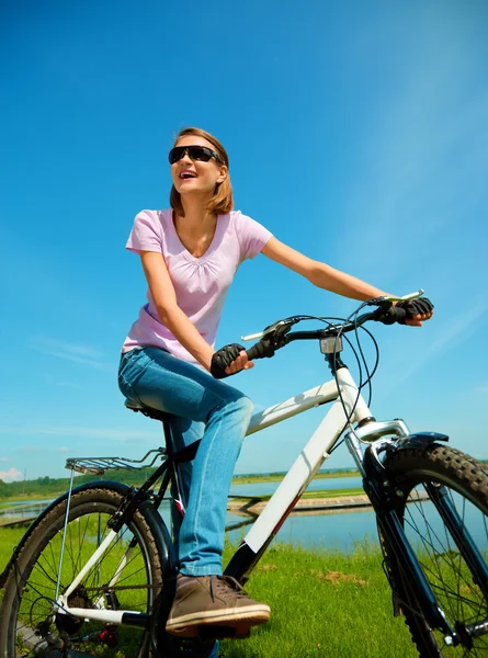 Jovem mulher está sentada em sua bicicleta — Fotografia de Stock