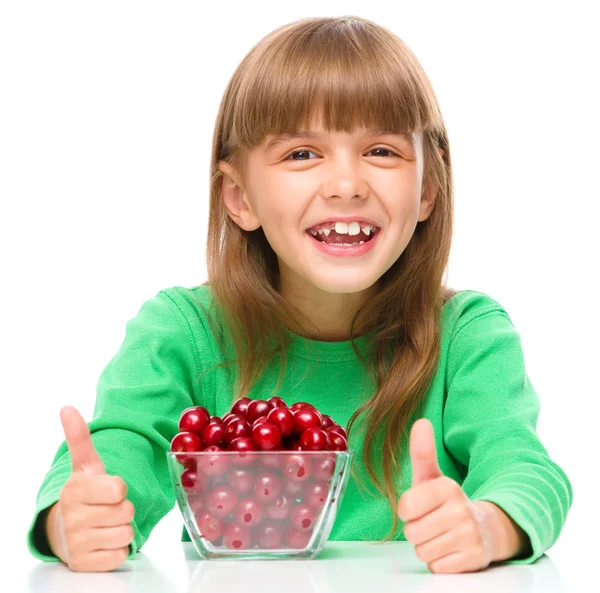 Cute girl is eating cherries showing thumb up sigh — Stock Photo, Image