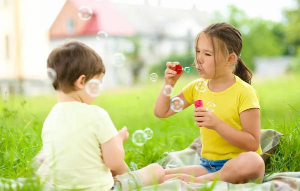 Ragazzina e ragazzo soffiano bolle di sapone — Foto Stock