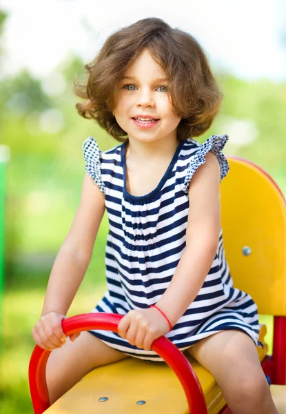 Young happy girl is swinging in playground — Stock Photo, Image