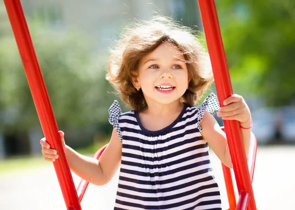 Junges glückliches Mädchen schaukelt auf Spielplatz — Stockfoto