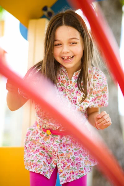 Menina bonito está jogando no parque infantil — Fotografia de Stock