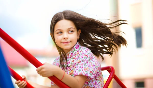 Giovane ragazza felice sta oscillando nel parco giochi — Foto Stock