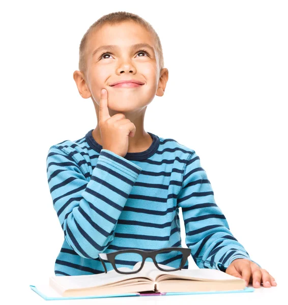 Young boy is daydreaming while reading book — Stock Photo, Image