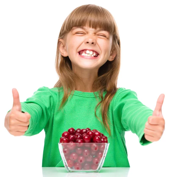 Cute girl is eating cherries showing thumb up sigh — Stock Photo, Image