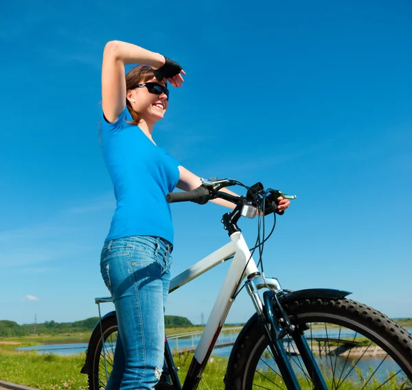 Mujer joven está de pie delante de su bicicleta — Foto de Stock