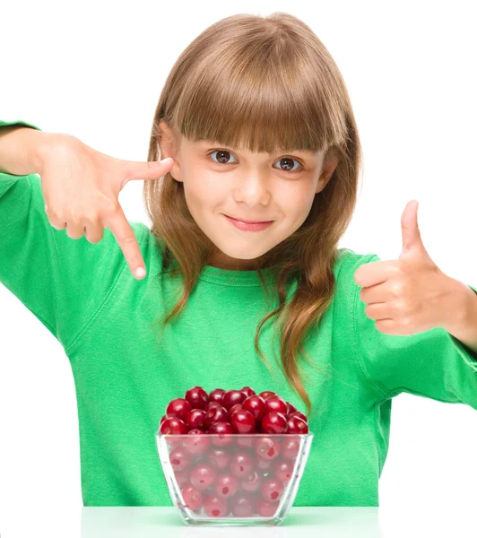 Cute girl is eating cherries showing thumb up sigh — Stock Photo, Image