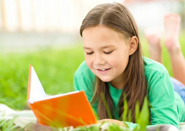 Маленька дівчинка читає книгу на відкритому повітрі — стокове фото