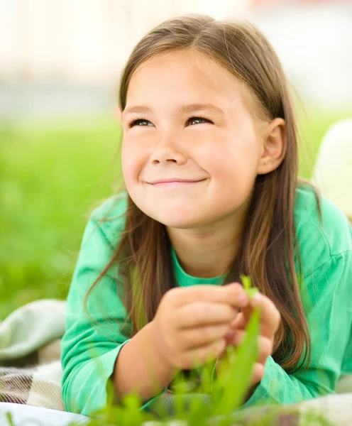 Porträt eines kleinen Mädchens auf grünem Gras liegend — Stockfoto