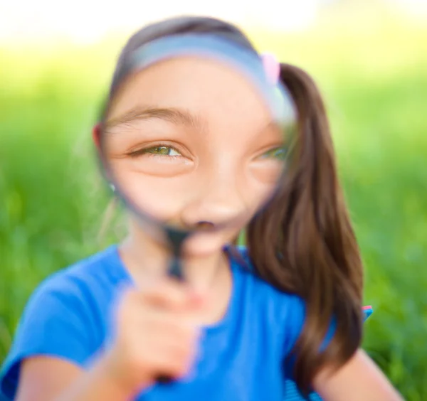 Kleines Mädchen schaut durch Lupe — Stockfoto