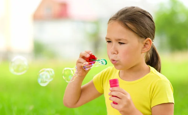 Liten flicka blåser en såpbubblor — Stockfoto