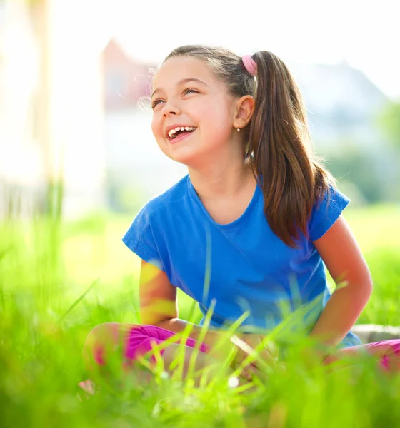 Porträtt av en liten flicka sitter på grönt gräs — Stockfoto