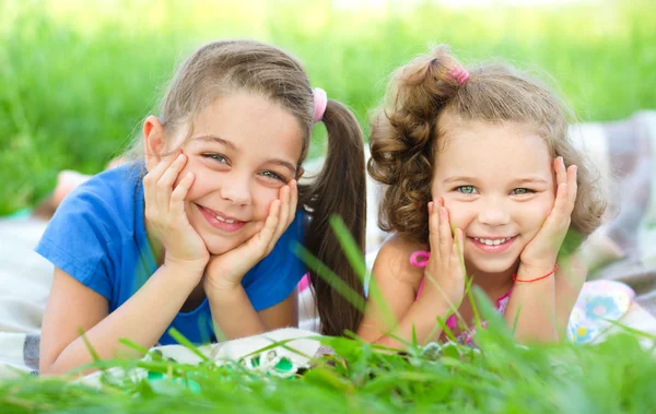 Duas meninas estão colocando na grama verde — Fotografia de Stock