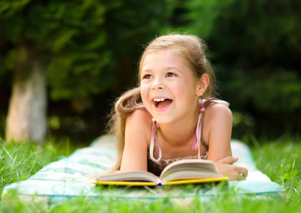 Little girl is reading a book outdoors — Stock Photo, Image