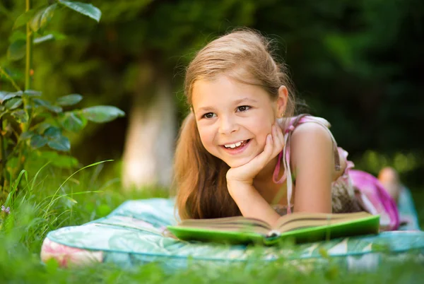 Little girl is reading a book outdoors — Stock Photo, Image