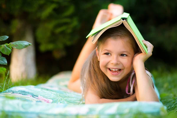 Küçük kız açık havada kitap altında saklanıyor어린 소녀가 야외에서 책 아래에 숨어 — Stok fotoğraf