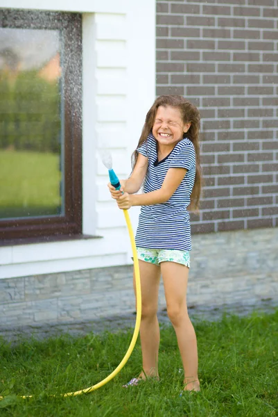 Šťastná dívka vylévání vody z hadice — Stock fotografie