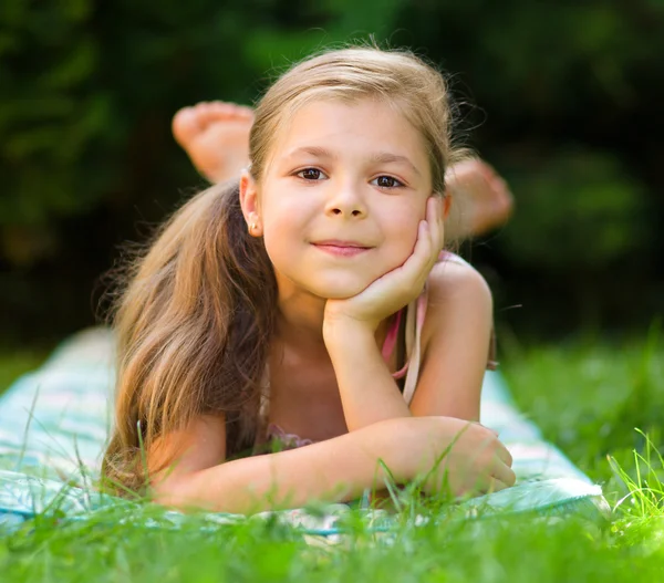 Portrait of a little girl laying on green grass Stock Image