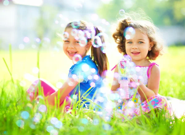 Deux petites filles soufflent des bulles de savon — Photo