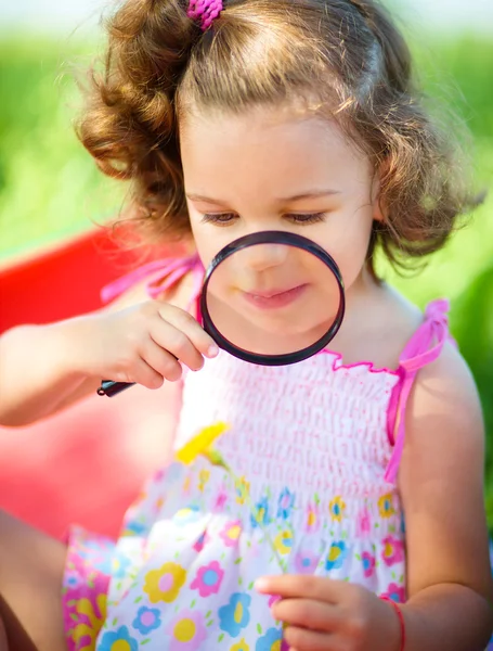 Junges Mädchen schaut Blume durch Lupe an — Stockfoto