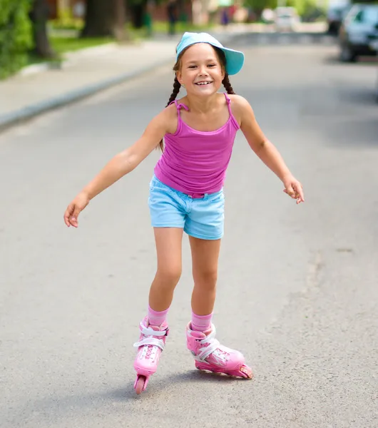 Happy little girl is skating on rollers — Stock Photo, Image