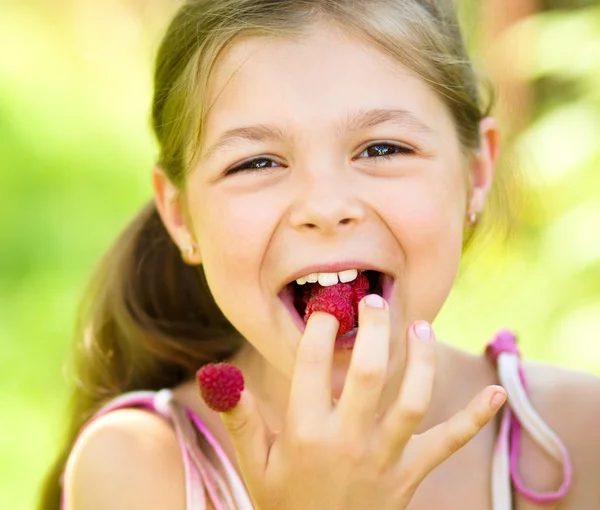 Young girl is holding raspberries on her fingers — Stock Photo, Image