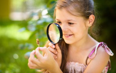 genç kız çiçek Büyüteç aracılığıyla bakarak