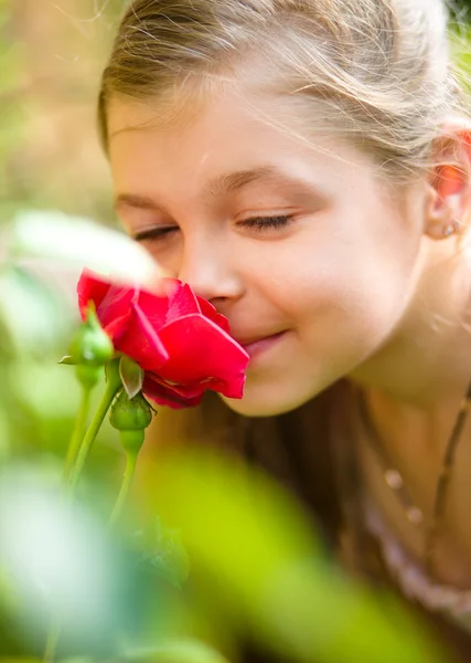 Retrato de una linda niña oliendo rosa — Foto de Stock