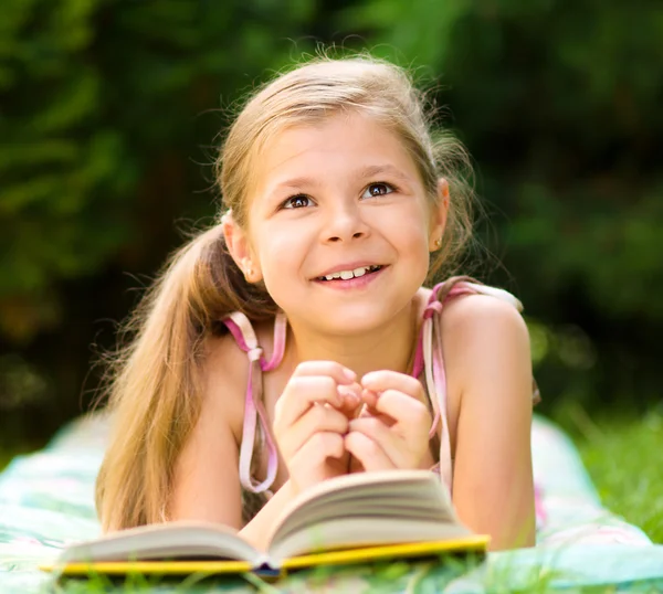 Liten flicka läser en bok utomhus — Stockfoto