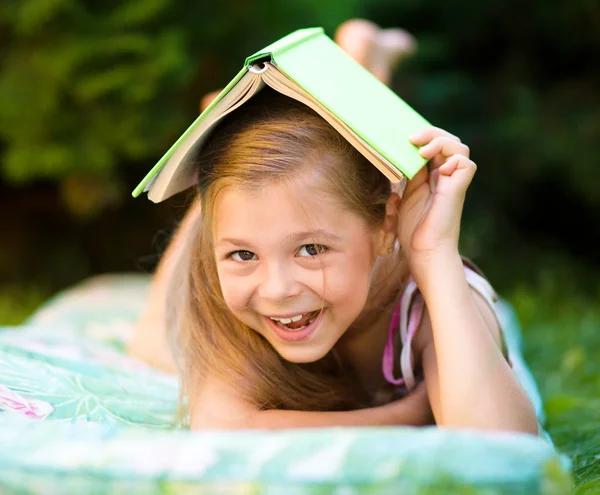 Little girl is hiding under book outdoors — Stock Photo, Image