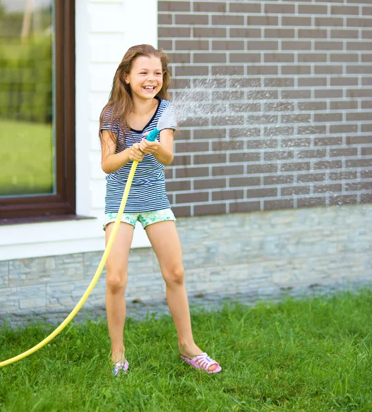 Glückliches Mädchen gießt Wasser aus einem Schlauch — Stockfoto