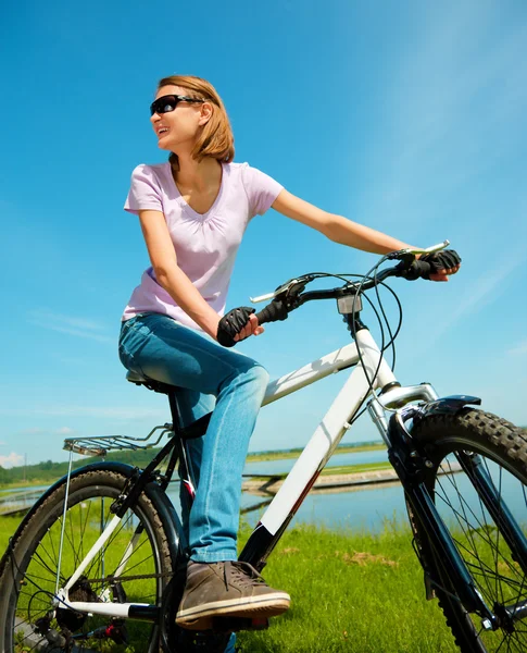 Jovem mulher está sentada em sua bicicleta — Fotografia de Stock