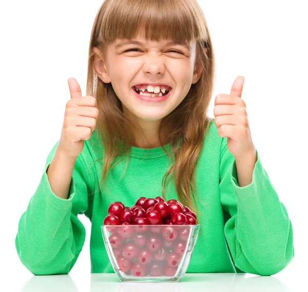 Cute girl is eating cherries showing thumb up sigh — Stock Photo, Image