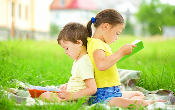 Niña y niño están leyendo libro al aire libre — Foto de Stock