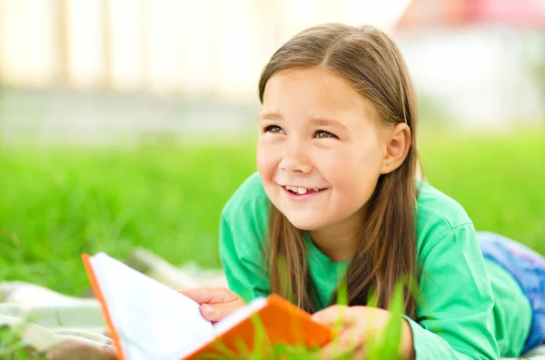 小さな女の子は屋外の本を読んでいます。 — ストック写真