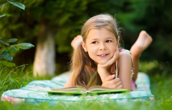 Liten flicka läser en bok utomhus — Stockfoto