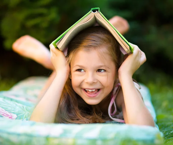 Little girl is hiding under book outdoors — Stock Photo, Image