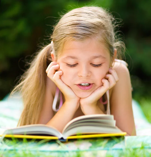 Little girl is reading a book outdoors — Stock Photo, Image