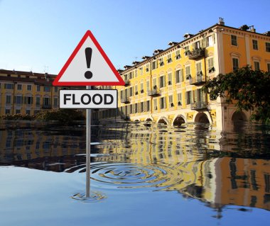 Suyun altındaki eski binalarla dolu bir şehir. FLOOD yazan bir tabela. İklim değişikliği ve çevre felaketi. Mavi gökyüzü arka planı. Değiştirilmiş resim.