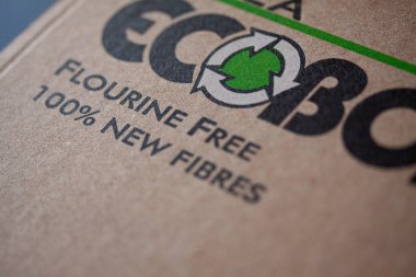 Recycling logo on sustainable compostable cardboard pizza box with text Flourine Free and 100 percent New Fibres. Shallow depth of field. Copenhagen, Denmark - april 22, 2022.