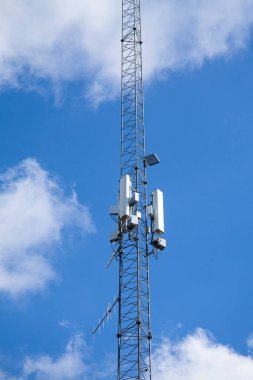 Hücre kulesi, telekomünikasyon direği mavi gökyüzüne ve beyaz bulutlara karşı.
