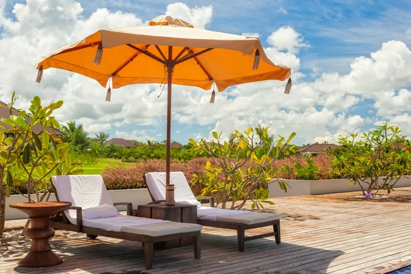 Cadeiras de praia Lounge com toalhas sob guarda-chuva na piscina o — Fotografia de Stock